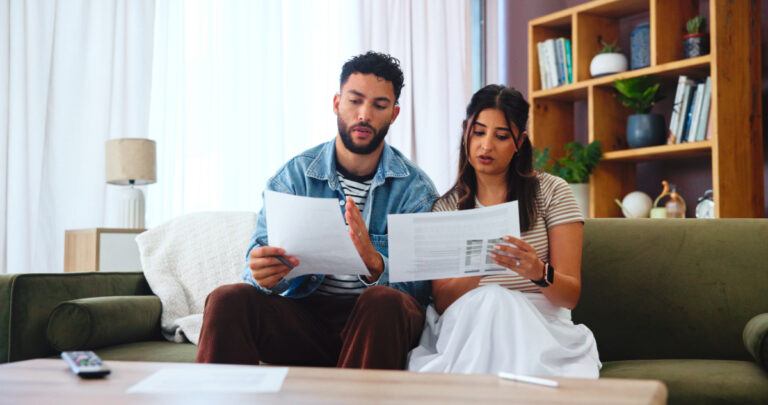 Couple on a sofa reading through paperwork