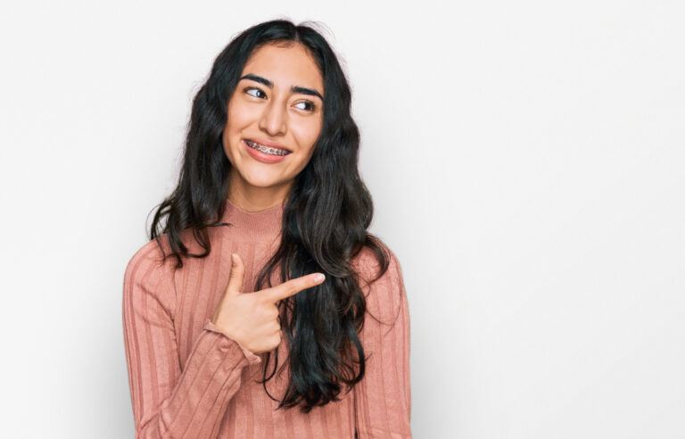 Smiling young woman with braces pointing to the side